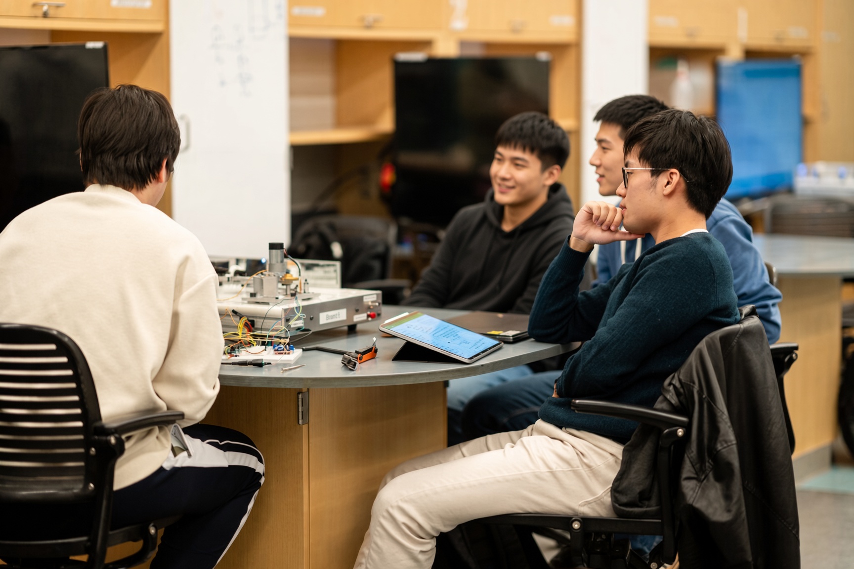 Four Gulfstone engineers reviewing a prototype assembly at a workbench in the workshop