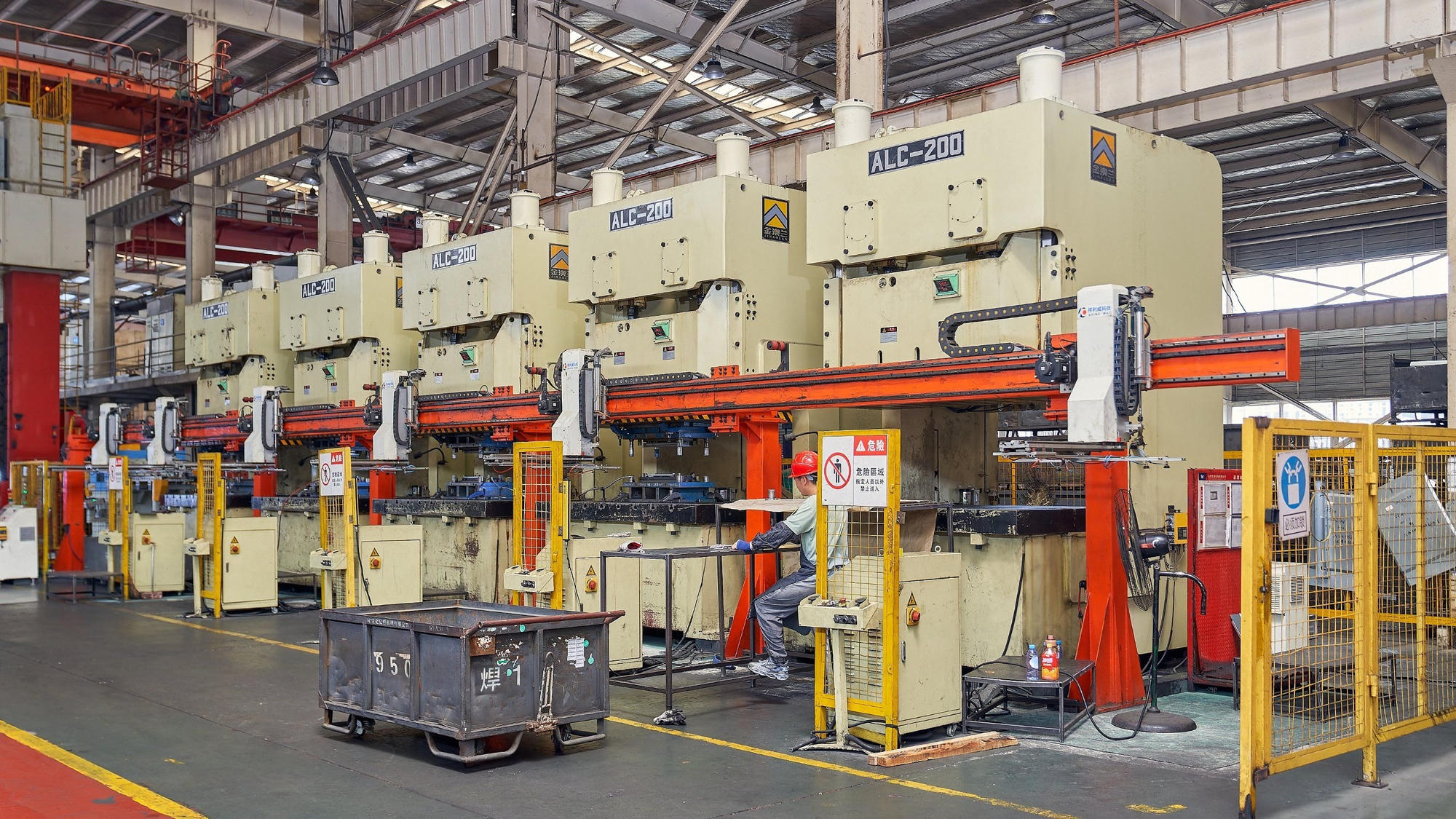 Row of ALC-200 hydraulic presses on the Gulfstone shop floor, with an automated transfer arm moving a panel into the press bed