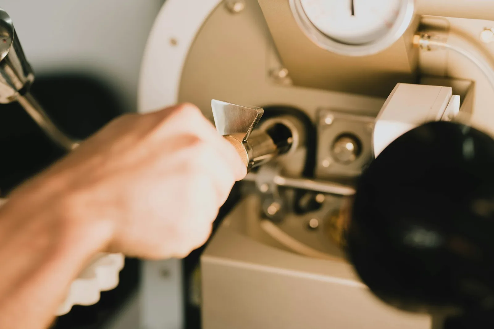 A hand turning a fitting on the face of a gas water heater with a spanner, the unit opened for service