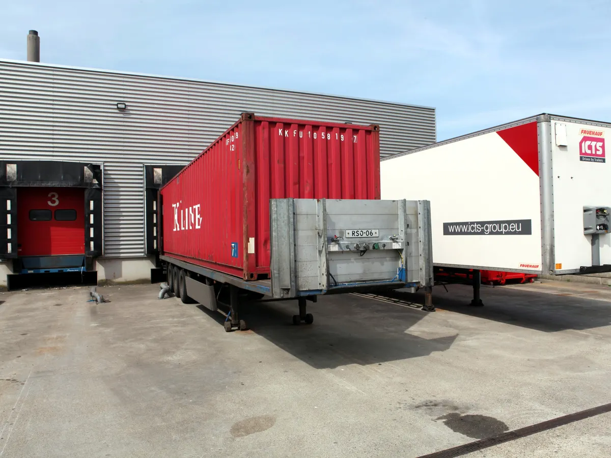 A shipping container backed onto a loading dock beside a box trailer