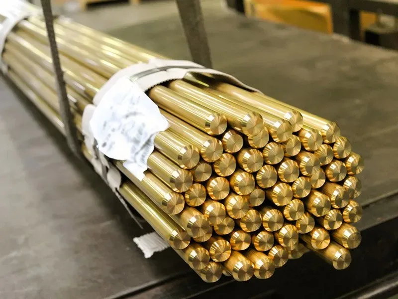 Banded bundles of brass bar stock on a factory bench, the raw material for valve bodies that may be machined off-site