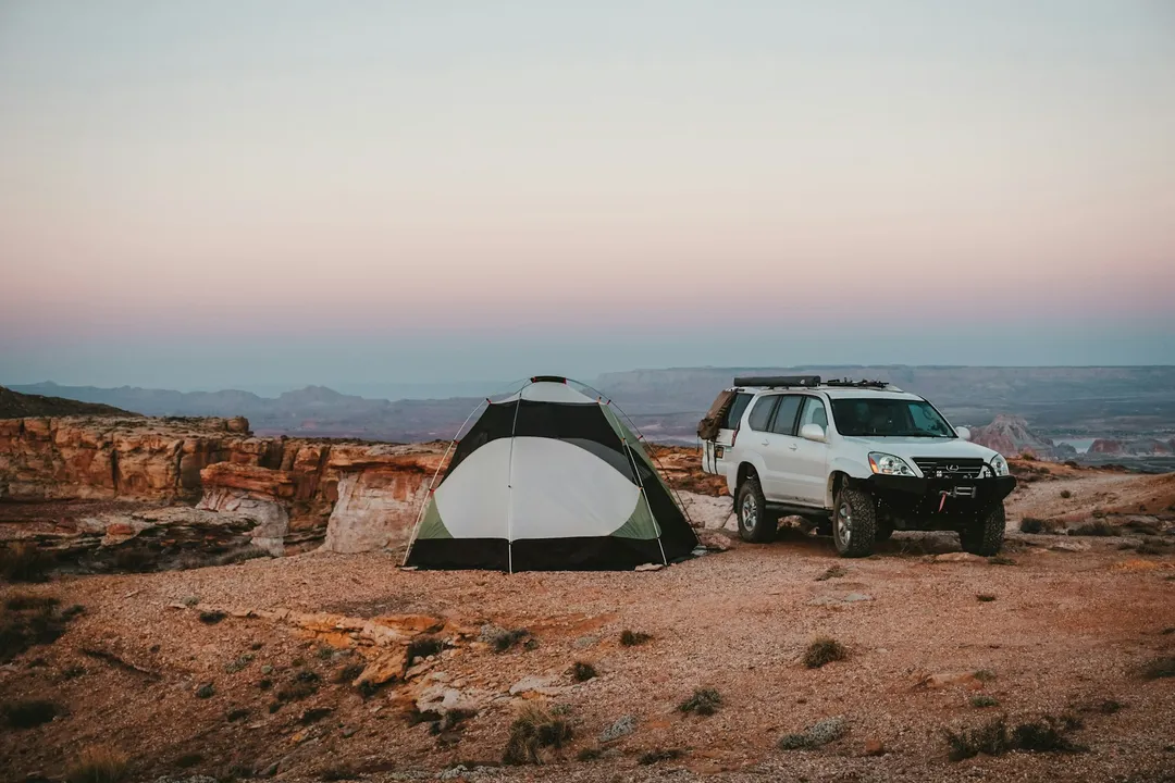 Roof-tent vehicle camped on a canyon rim at dusk