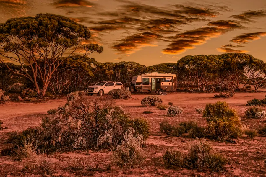 A vehicle parked in open red desert country under a wide sky