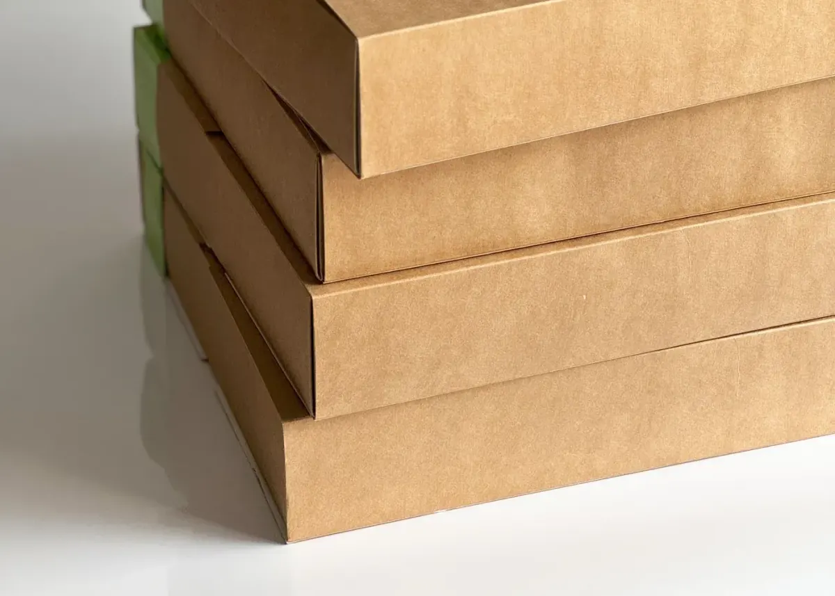 Three stacked plain kraft cardboard boxes on a white background