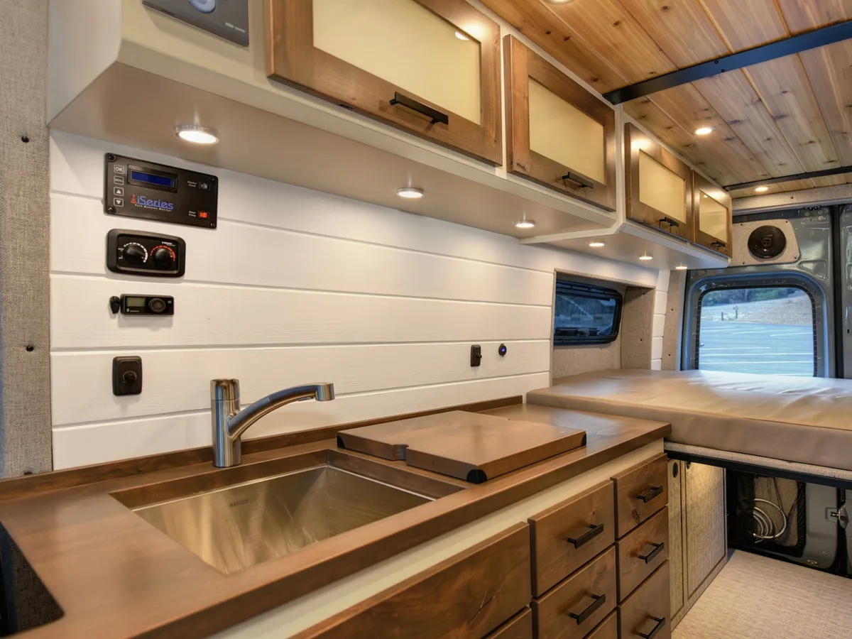 The galley of a campervan conversion: sink, worktop and cabinetry in warm timber