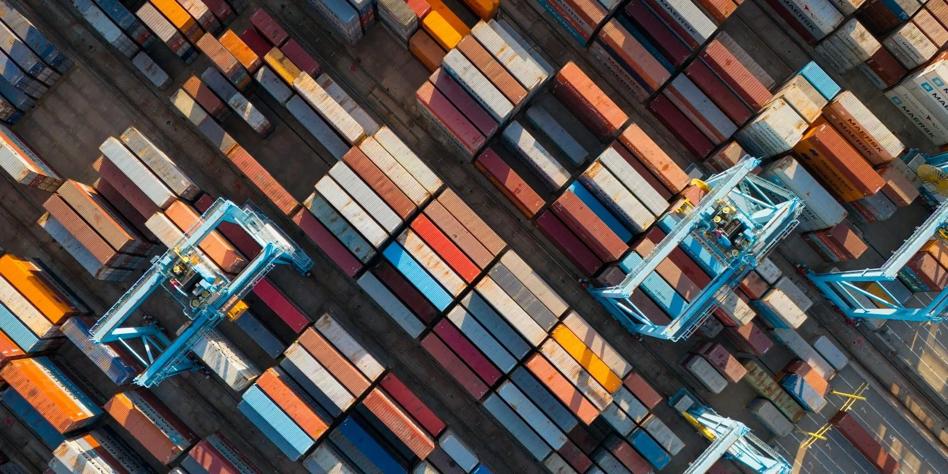Aerial view of a container terminal: stacked colourful containers between gantry cranes