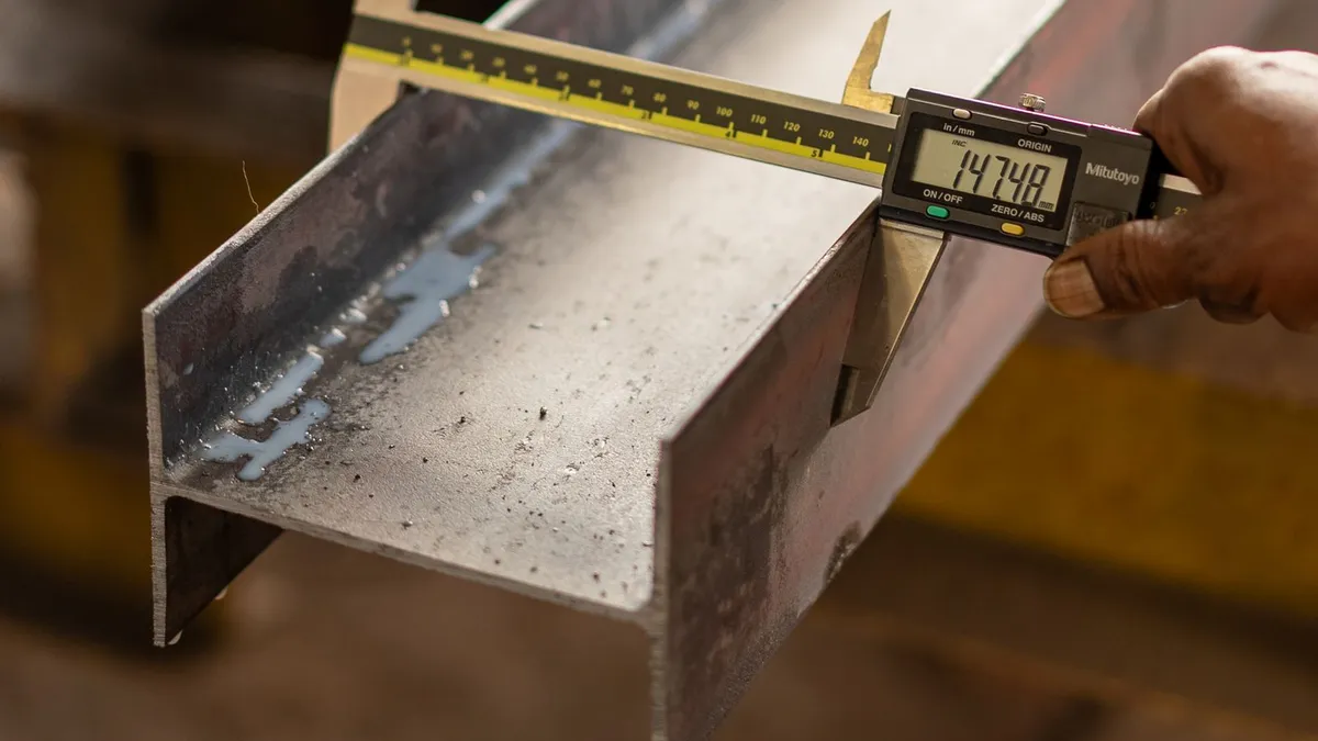 A digital caliper measuring a machined metal component on a bench
