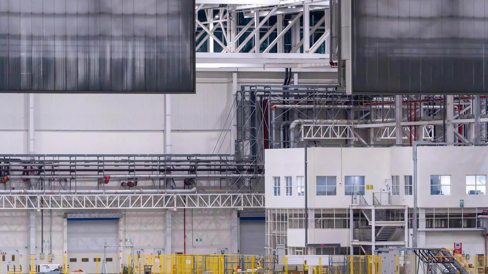 A large industrial production hall with automated equipment and pipework along the walls