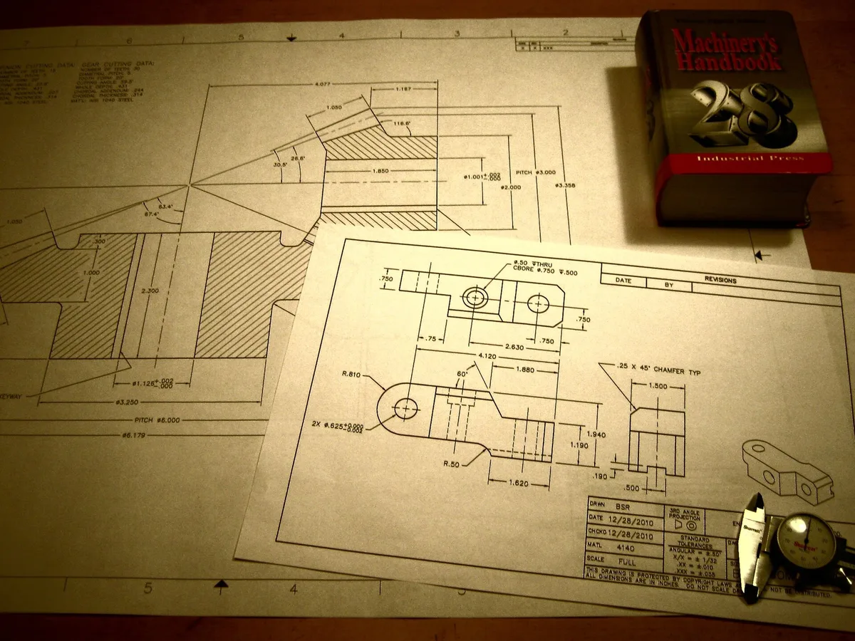 Technical drawings and a measured component laid out on a development bench
