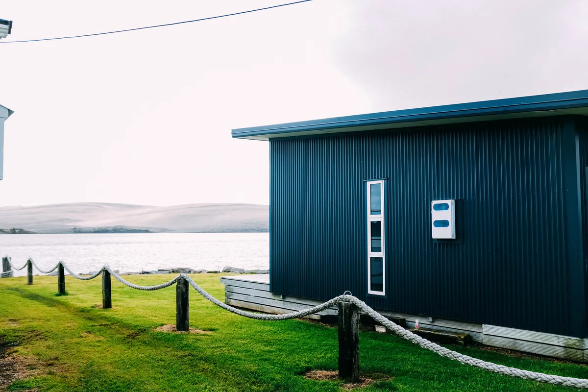 A dark corrugated-metal outbuilding standing in an open field