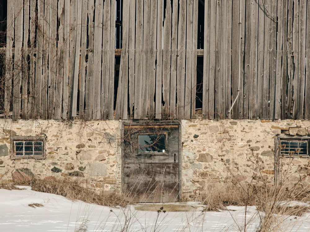 A weathered timber wall on a stone foundation, the kind of exterior face a unit is mounted on
