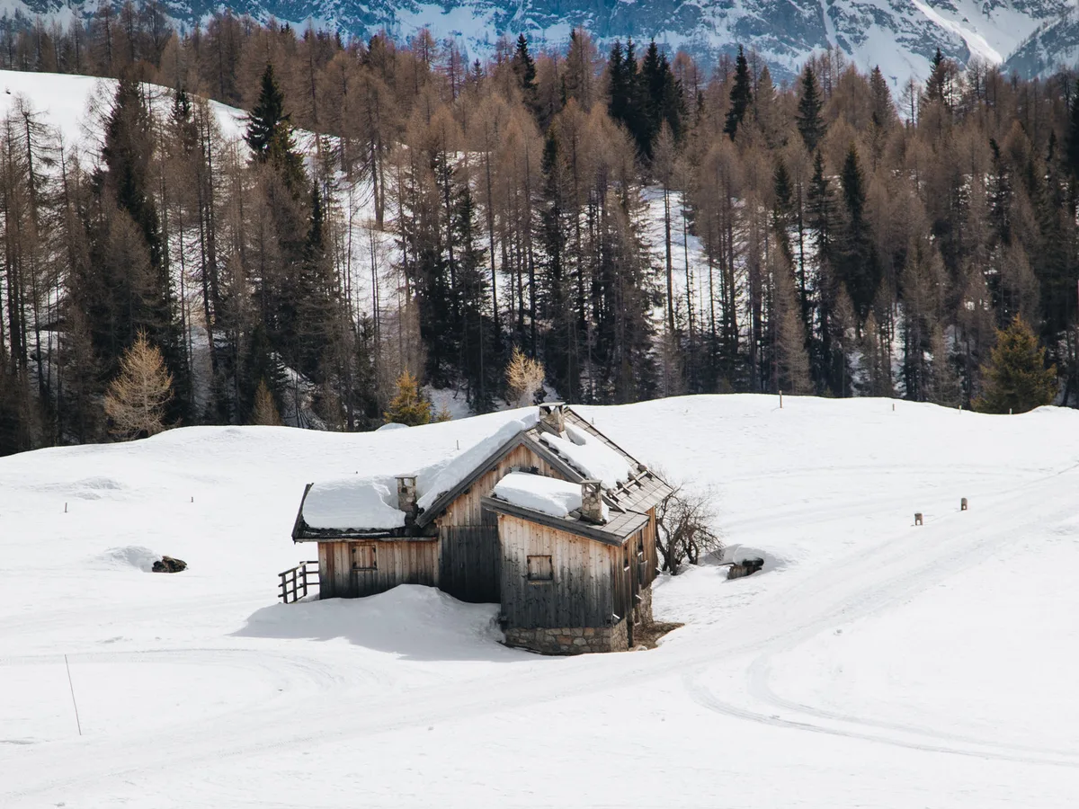 An isolated timber cabin standing in deep snow with no tracks approaching it