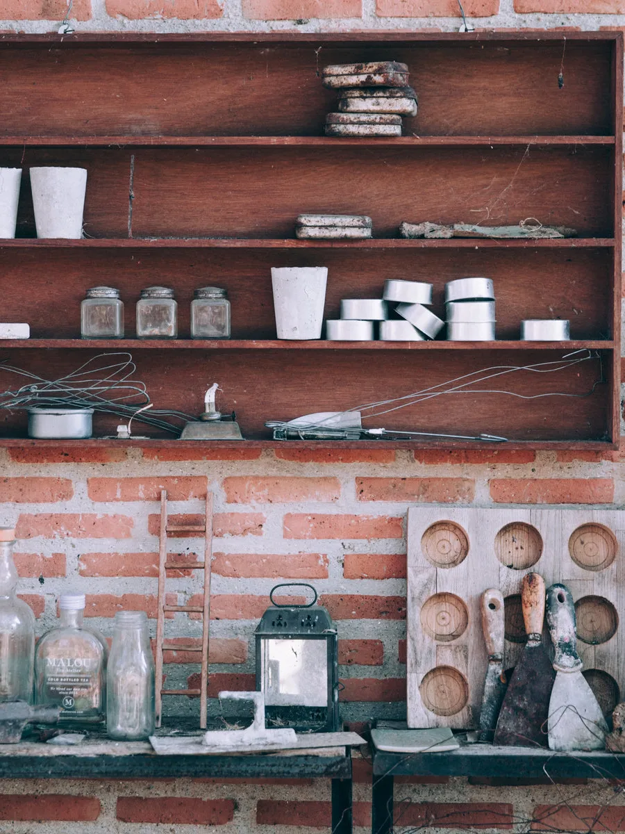The inside of a working outbuilding — a bench, tools and shelves against a bare brick wall, no plumbing run