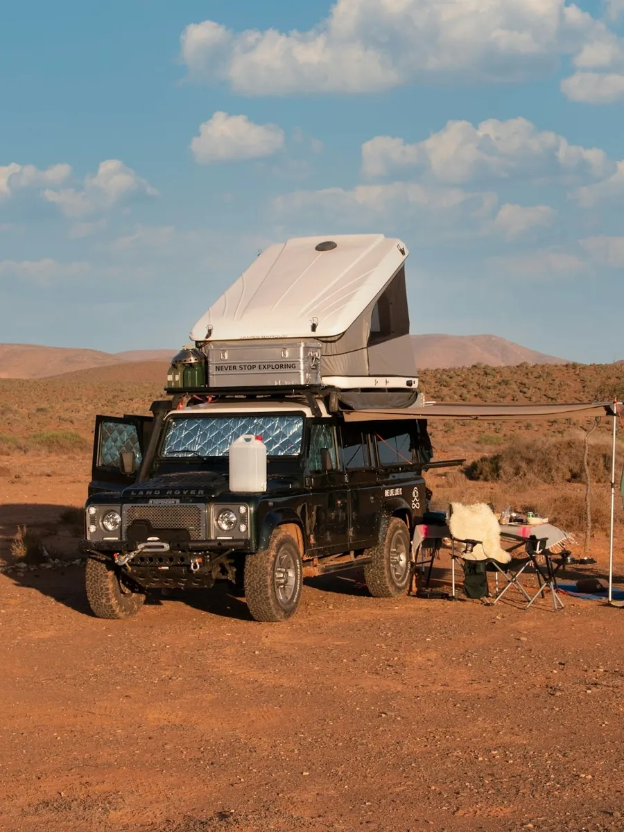 A four-wheel-drive vehicle with a rooftop tent and an awning set up in red desert country