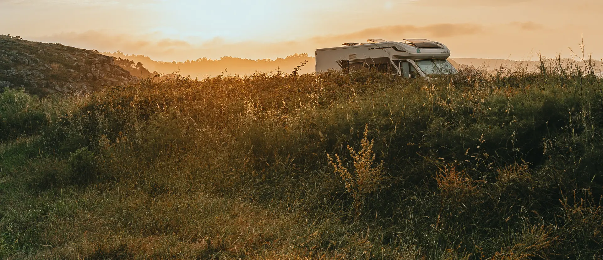 Campervan parked on a grassy headland at sunrise, the off-grid use the portable build is carried for