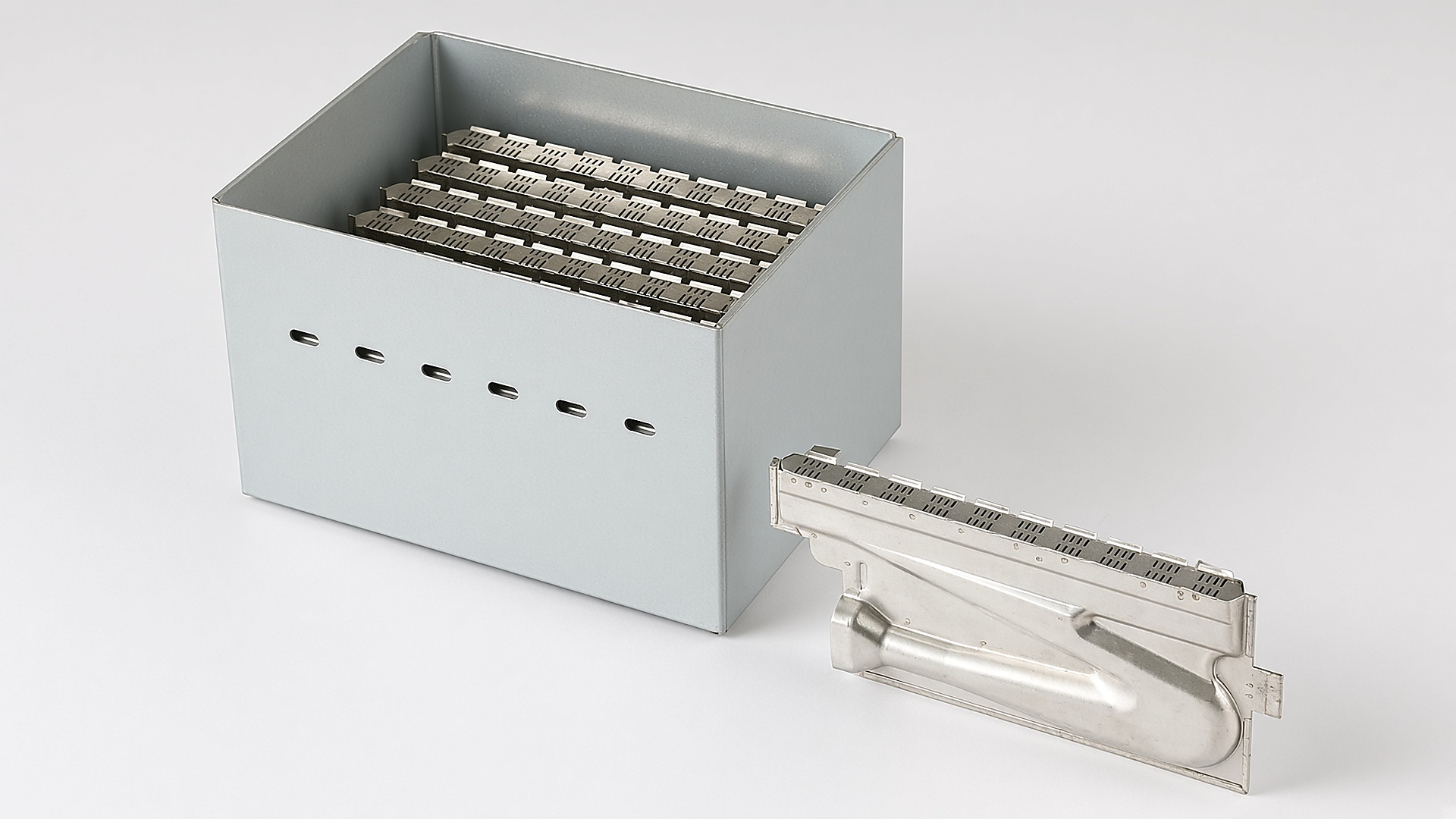 The Gulfstone RV water heater premix burner: a stainless burner box with its slotted burner bar laid beside it, on a white ground
